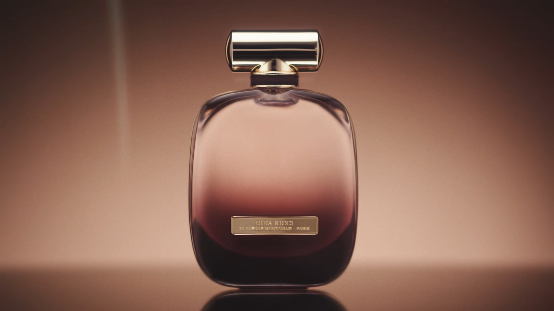 Front view of the Nina Ricci L’Extase bottle against a warm brown background.