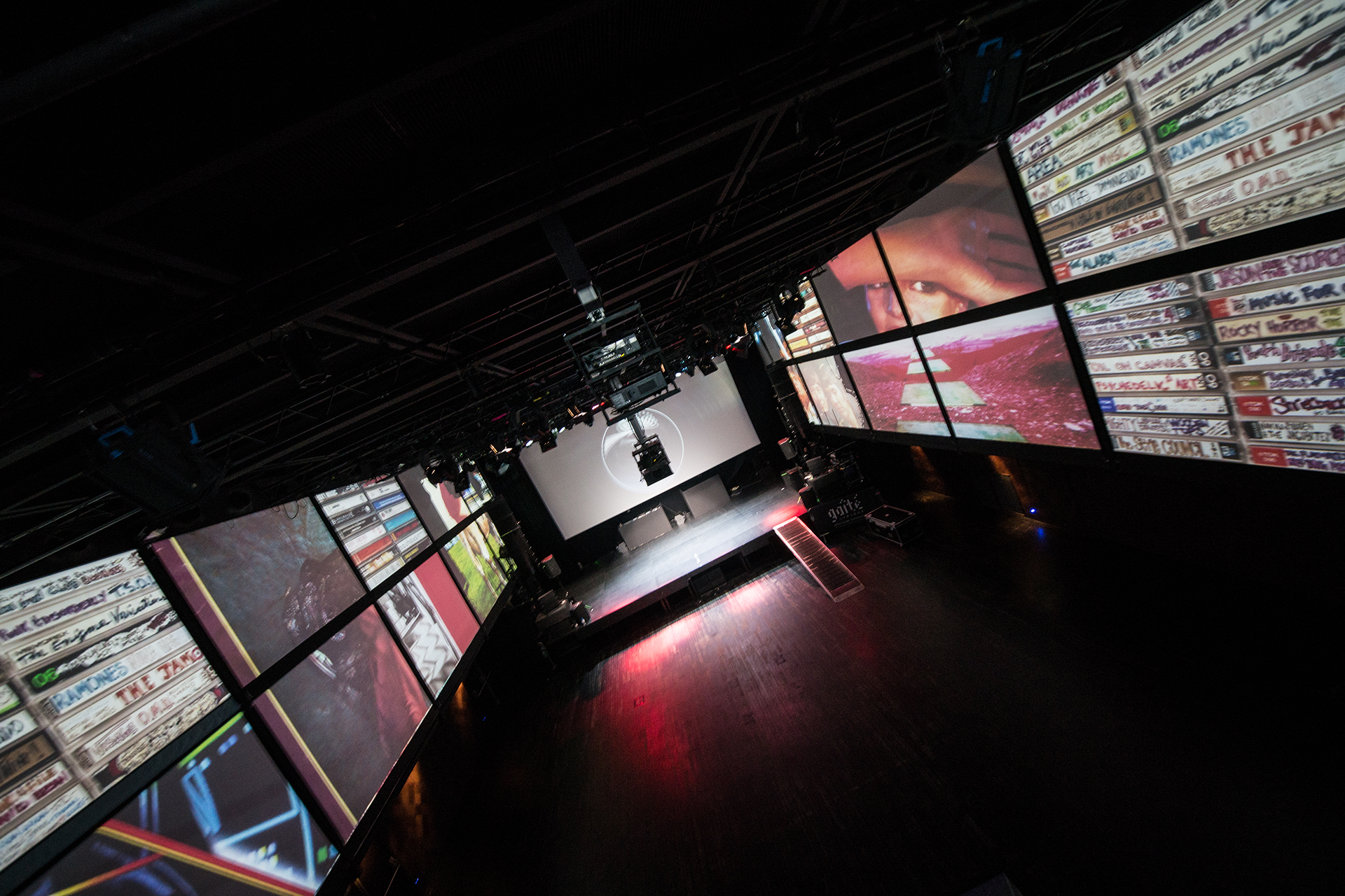 Album artwork and cassette imagery projected across the side walls and stage.