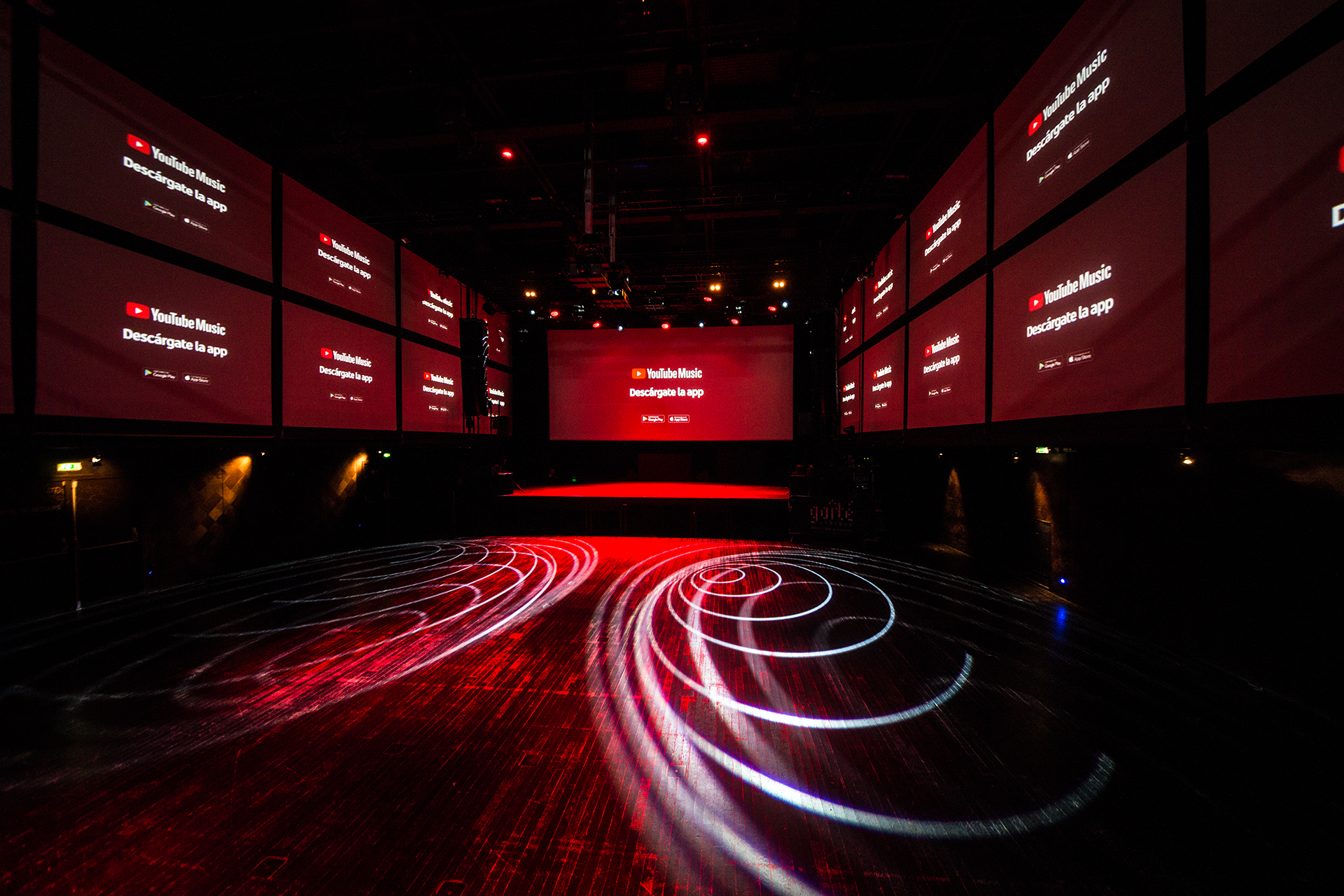 YouTube Music launch screens and circular floor lighting in the large room.